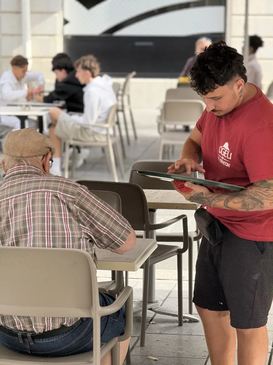 Un serveur du Cristal prenant la commande de clients installés en terrasse