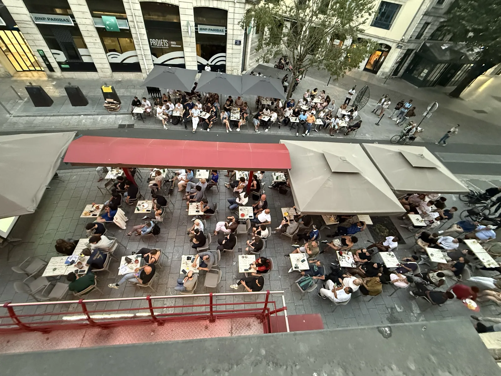 Vue en surplomb de la terrasse et des stores rouges du Cristal à Pau